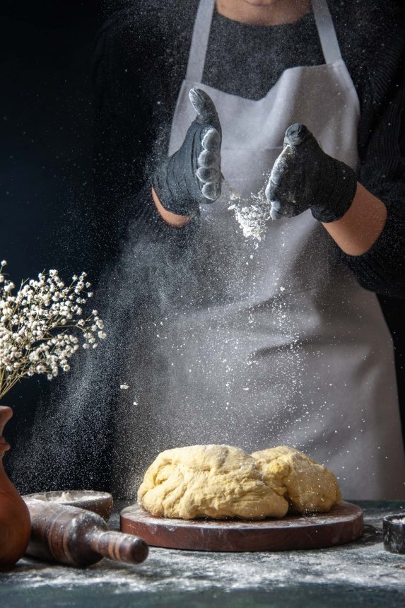 front-view-female-cook-rolling-out-dough-with-flour-dark-job-raw-dough-hotcake-bakery-pie-oven-pastry.jpg