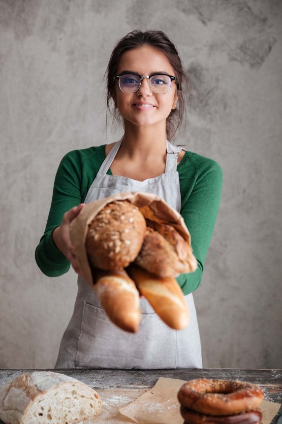 vertical-image-female-baker-showing-bag-with-bread.jpg